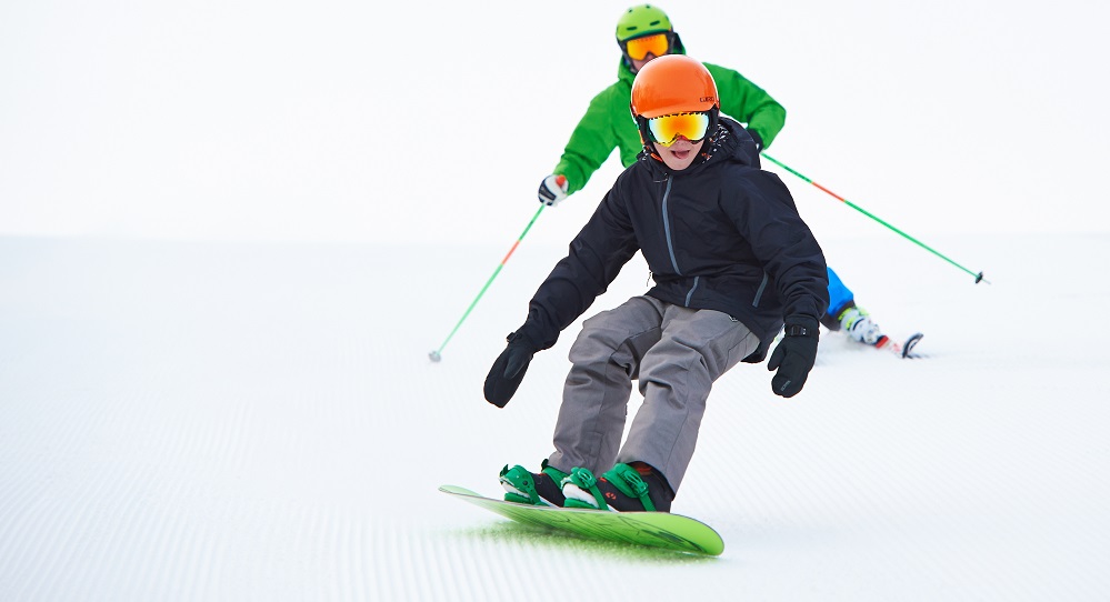 A skier and a snowboarder flying down the snowy trail. 