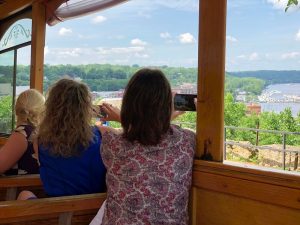 Two women looking out the window of the Stillwater Trolly and taking a picture of the lift bridge. 