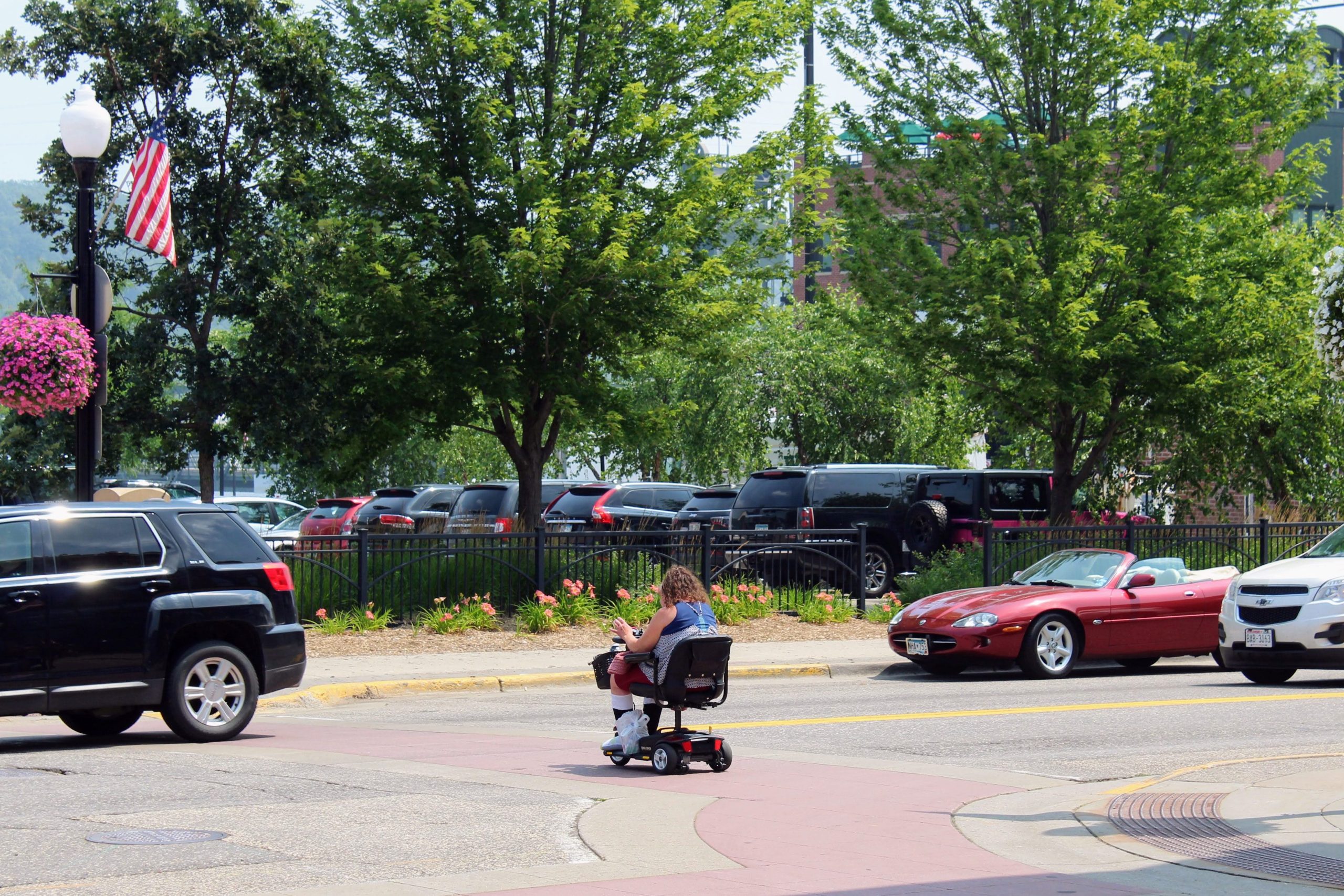 Woman crossing street in mobility device, accessible Stillwater