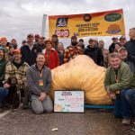 A group of people posing with the heaviest pumpkin.