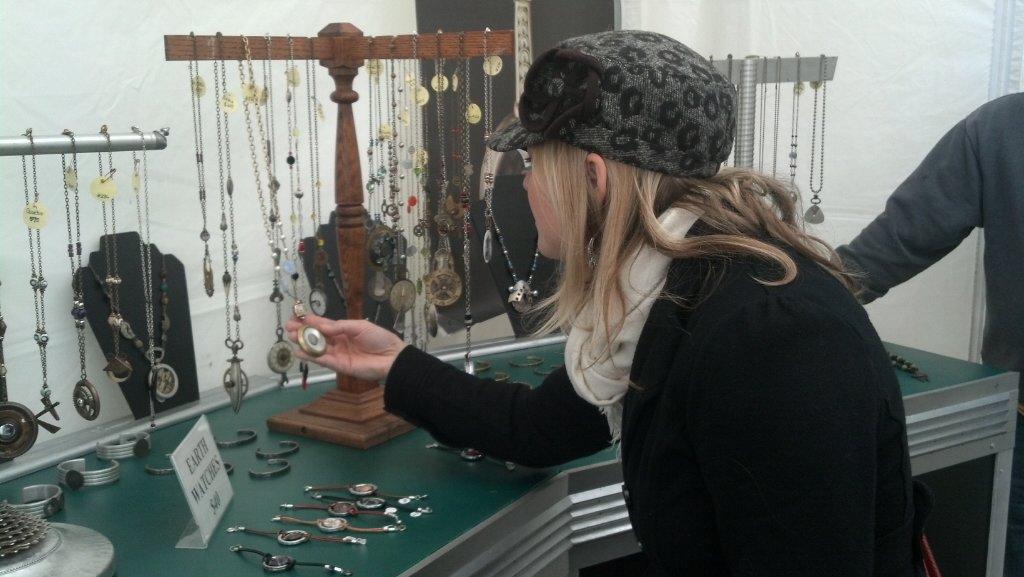 Person looks at necklaces and watches at the Rivertown Fall Art Festival