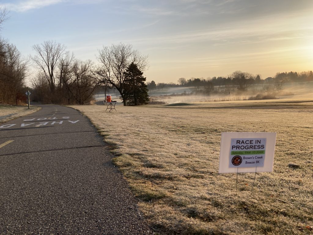 The empty running trail for the Brown's Creek Breeze in early morning. There's a sign that says 'race in progress.'