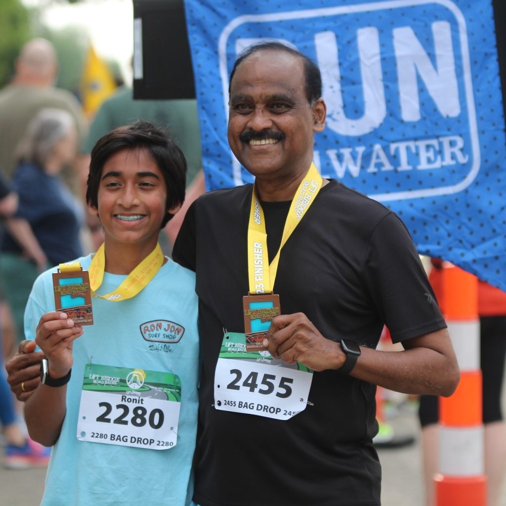 two racers hold up their medals at the finish line of the Lift Bridge Road Race