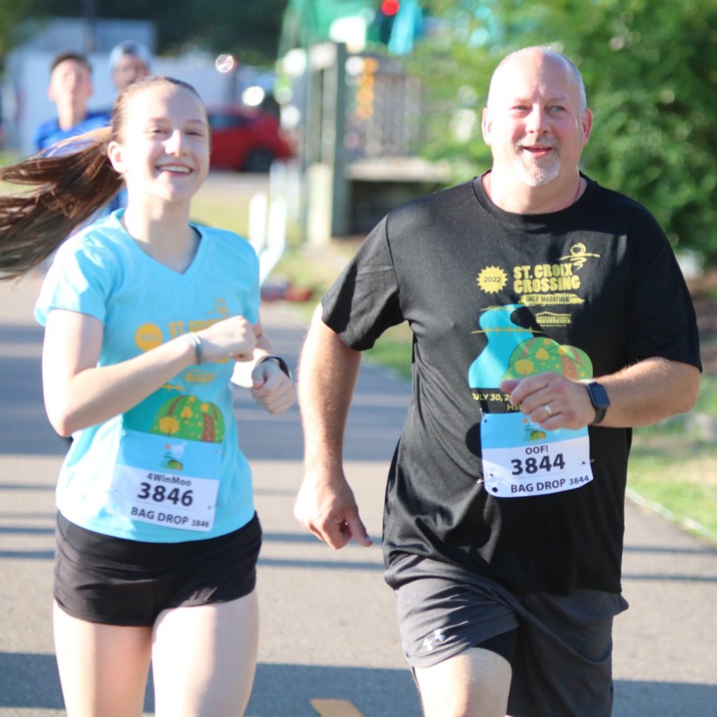 Two racers run the Lift Bridge Road Race on a sunny day